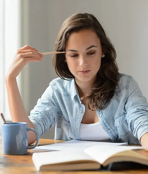 Royalty-free photo of a teenage girl studying and reading a book at home, deeply concentrating and looking down. Ideal for those seeking dissertation data analysis services, capturing the essence of focused academic research and analysis.