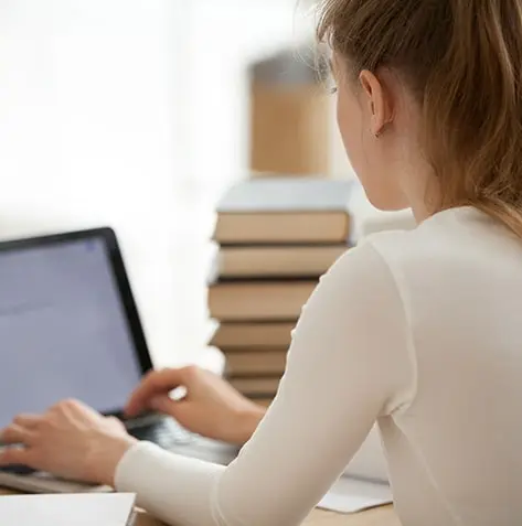 Young beautiful college student girl studying for a university exam, feeling stress and seeking help under test pressure. She sits on a desk with a book, reflecting the challenges of youth education. Relevant for those in need of dissertation methodology help, navigating the complexities of academic research.
